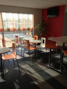 a dining room with tables and chairs and a window at Première Classe Istres in Istres