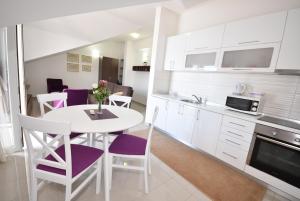 une cuisine avec une table blanche et des chaises violettes dans l'établissement Grifone Coastline, à Herceg-Novi