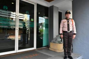a man in uniform standing in front of a building at Happyland Mansion in Bangkok