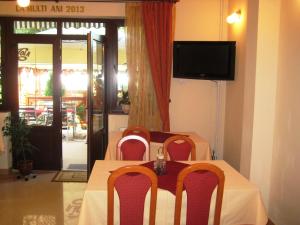 een eettafel met stoelen en een televisie bij Pensiunea Speranta in Sovata