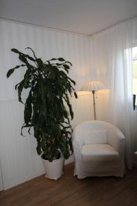 a white chair and a potted plant in a room at Lövås Gård Koppera in Charlottenberg