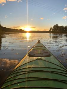 a kayak on a lake with the sun setting at Lövås Gård Koppera in Charlottenberg