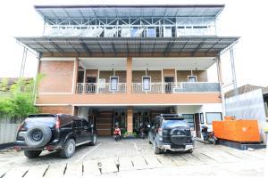 two cars parked in a parking lot in front of a building at Hotel Celia in Samarinda