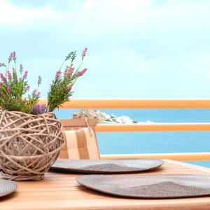 stół z dwoma talerzami i wazon z kwiatami w obiekcie M&N Luxury Family Apartment 10meters from the Sea w mieście Agia Pelagia