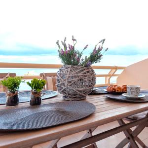a table with plates and a vase with flowers on it at M&N Luxury Family Apartment 10meters from the Sea in Agia Pelagia