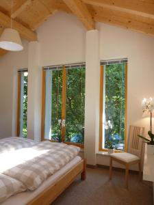 a bedroom with windows and a bed and a chair at Harzer Feriengarten 5***** in Bad Suderode