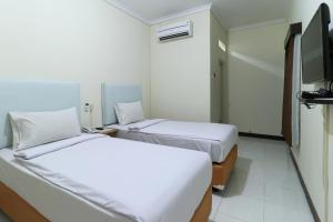a hotel room with two beds and a tv at Hotel Celia in Samarinda