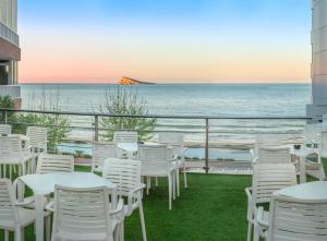 a balcony with white chairs and tables and the ocean at Hotel RH Corona del Mar 4* Sup in Benidorm