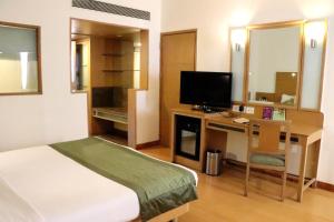 1 dormitorio con 1 cama y escritorio con TV en VITS Aurangabad, en Aurangabad