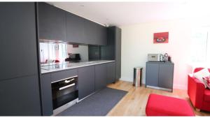 a kitchen with black cabinets and a red chair at ★ Luxury Oxford Apartment ★ Sleeps 4, Free Parking in Oxford