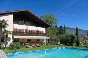 ein Haus mit einem Pool neben einem Gebäude in der Unterkunft Hotel Burgleitenhof in Lana