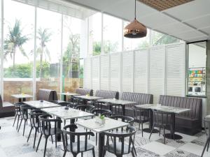 uma sala de jantar com mesas, cadeiras e janelas em d'primahotel Airport Jakarta 2 em Tangerang