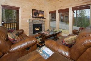 ein Wohnzimmer mit einem Ledersofa und einem Kamin in der Unterkunft A Suite Mountain Retreat Cabin in Pigeon Forge