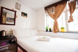 Un pequeño dormitorio con una cama blanca y una ventana en Comfort Guest House en Hong Kong