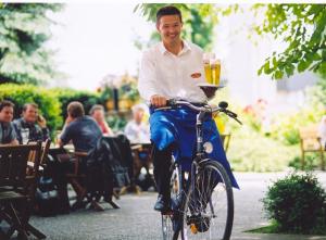 
a man riding a bike with a bottle of beer at Gasthof Böhm in Persenbeug
