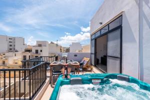 - Balcón con piscina y mesa en un edificio en Seashells Sea View Penthouse with private Hot Tub & large sunny terrace with stunning views - by Getwaysmalta en St. Paul's Bay