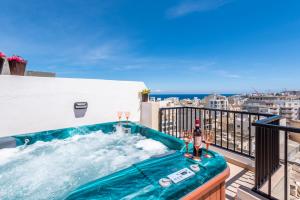 bañera de hidromasaje en el balcón con vistas a la ciudad en Seashells Sea View Penthouse with private Hot Tub & large sunny terrace with stunning views - by Getwaysmalta en St. Paul's Bay