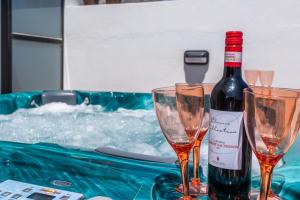 Una botella de vino y dos copas en una mesa. en Seashells Sea View Penthouse with private Hot Tub & large sunny terrace with stunning views - by Getwaysmalta en St. Paul's Bay