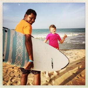 a man and a little girl holding a surfboard on the beach at Royal Point Arugambay in Arugam Bay