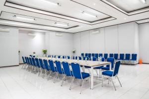 einen Konferenzraum mit einem langen Tisch und blauen Stühlen in der Unterkunft LeGreen Suite Supomo in Jakarta