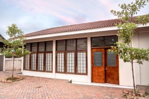 ein Haus mit Holztüren und einer Ziegelsteinfahrt in der Unterkunft LeGreen Suite Supomo in Jakarta