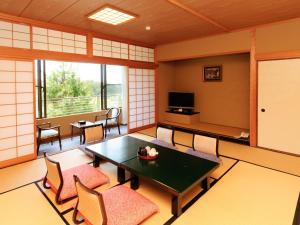 a room with a table and chairs and a television at Ikoi no mura Notohanto in Shika