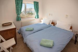 a bedroom with two beds and a desk and a window at Cottage 215 - Claddaghduff in Cleggan