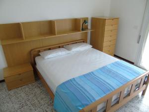 a bedroom with a bed with a wooden headboard and shelves at Residenza Sporting in Lignano Sabbiadoro