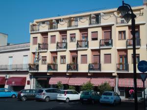 um edifício alto com carros estacionados em frente em Hotel Ristorante Mommo em Polistena