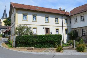une grande maison blanche avec une haie devant elle dans l'établissement Villa Merzbach - Wohnen wie im Museum mit Komfort, à Untermerzbach