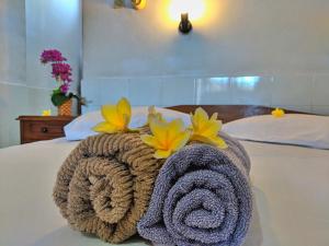 a towel on a bed with flowers on it at Serangan Inn II in Padangbai