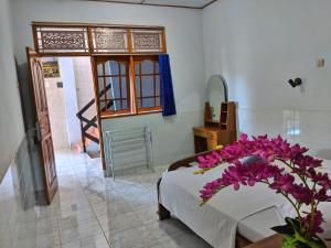 een slaapkamer met een bed met paarse bloemen erop bij Serangan Inn II in Padangbai