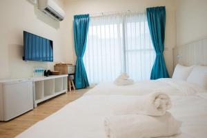 1 dormitorio con 2 camas blancas y cortinas azules en 凱悅會館, en Hengchun