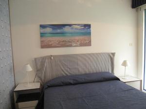 a bedroom with a bed with two lamps and a painting at Appartamento Aquileia in Lido