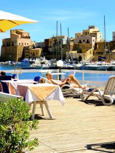 a man is sitting on a chair on a dock at Hotel Cala Marina in Castellammare del Golfo