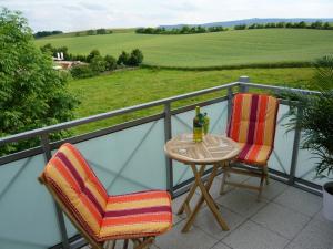 2 Stühle und ein Tisch mit einer Flasche Wein auf dem Balkon in der Unterkunft Pummpälzhof in Bad Salzungen