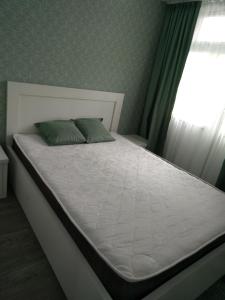 a bed in a bedroom with a white mattress and a window at Apartment Eteri in Batumi