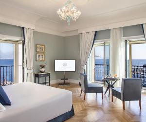 a bedroom with a bed and views of the ocean at Grand Hotel Santa Lucia in Naples