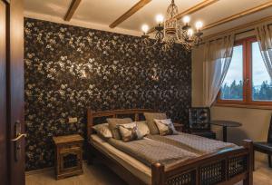 Schlafzimmer mit einem Bett mit Blumentapete in der Unterkunft Góralski Dwór in Duszniki-Zdrój