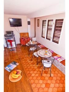 sala de estar con mesas, sillas y TV en Villa Mia Casa en Supetar