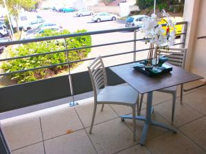 a table and chairs on a balcony with a view of a street at Résidence Thalacap in Cap d'Agde
