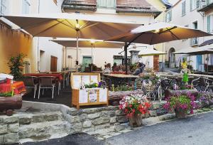 an outdoor patio with tables and umbrellas and flowers at Les Gentianes in Allos