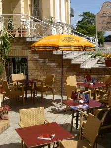 un patio con mesas, sillas y una sombrilla en Hotel Villa Auguste Viktoria, en Ahlbeck