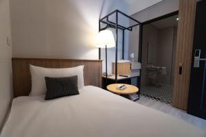 - une chambre avec un grand lit blanc et une salle de bains dans l'établissement Feng-Chi Inn, à Taïtung