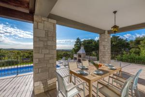 taras ze stołem i krzesłami oraz basenem w obiekcie Villa Sterpazzi - near Porec with Sea View, private Jacuzzi, Sauna and Pool w mieście Višnjan
