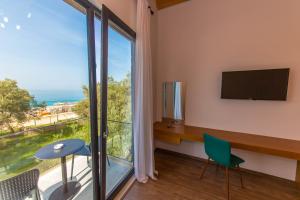 a room with a desk and a tv and a window at Alban Eco Hotel in Dhërmi