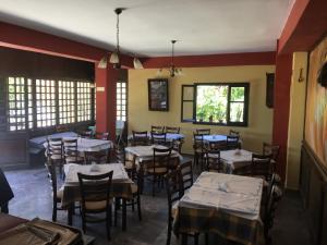 a dining room with tables and chairs and windows at Pension Skala in Ágios Matthaíos