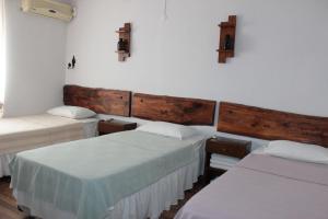 three beds in a room with white walls at Tuncay Pension in Selcuk