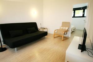 ein Wohnzimmer mit einem schwarzen Sofa und einem Stuhl in der Unterkunft OPO.APT - Art Deco Apartments in Oporto's Center in Porto