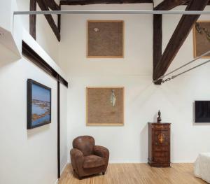 a living room with a chair and paintings on the wall at Mitodea - Residenza d'Epoca in Bologna